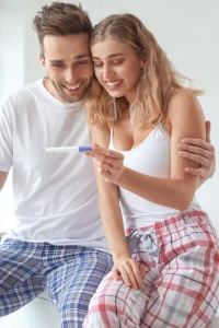 Una coppia sorride guardando un test di gravidanza